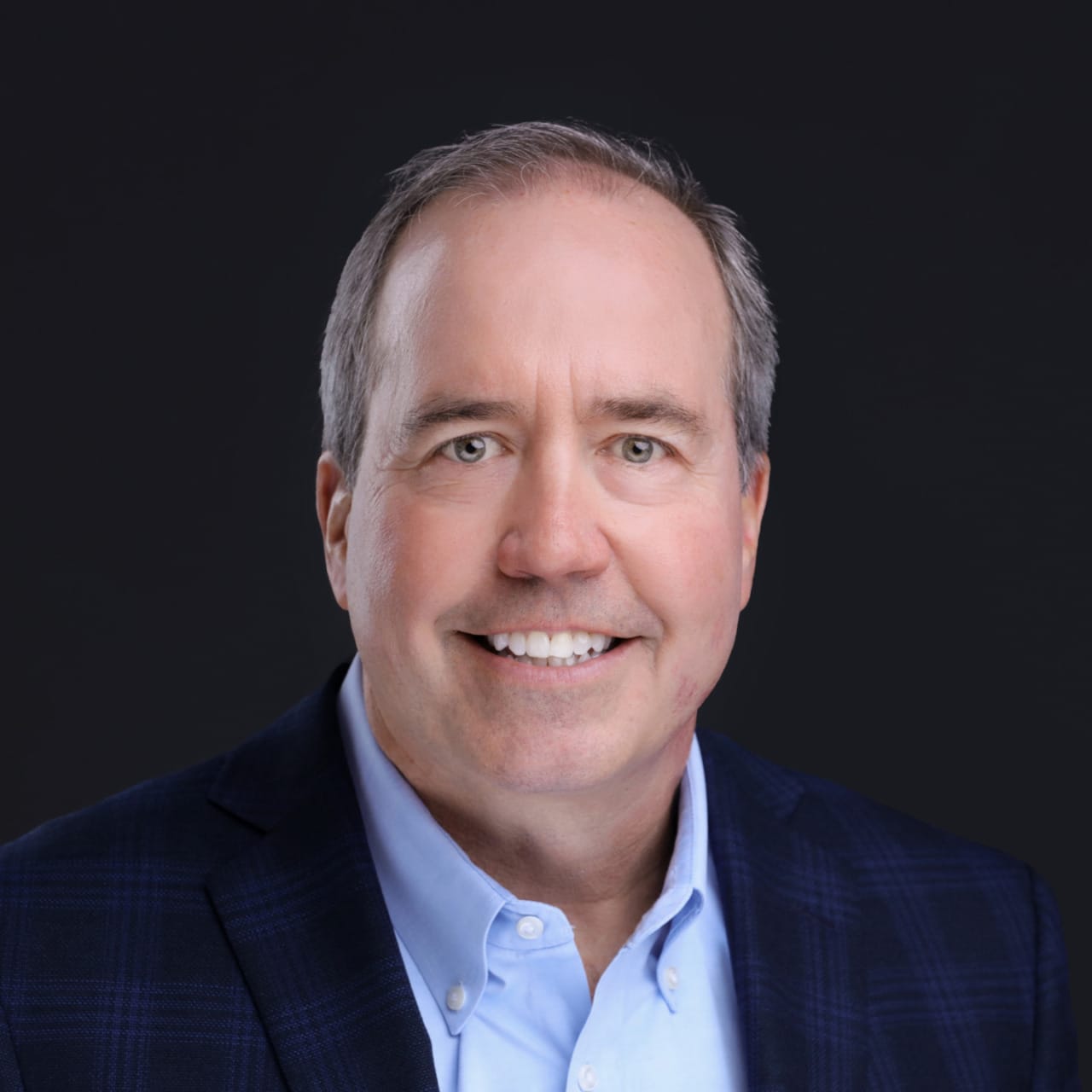 Businessman in a suit smiling against a dark background