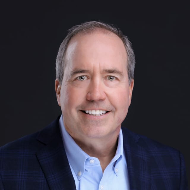 Businessman in a suit smiling against a dark background