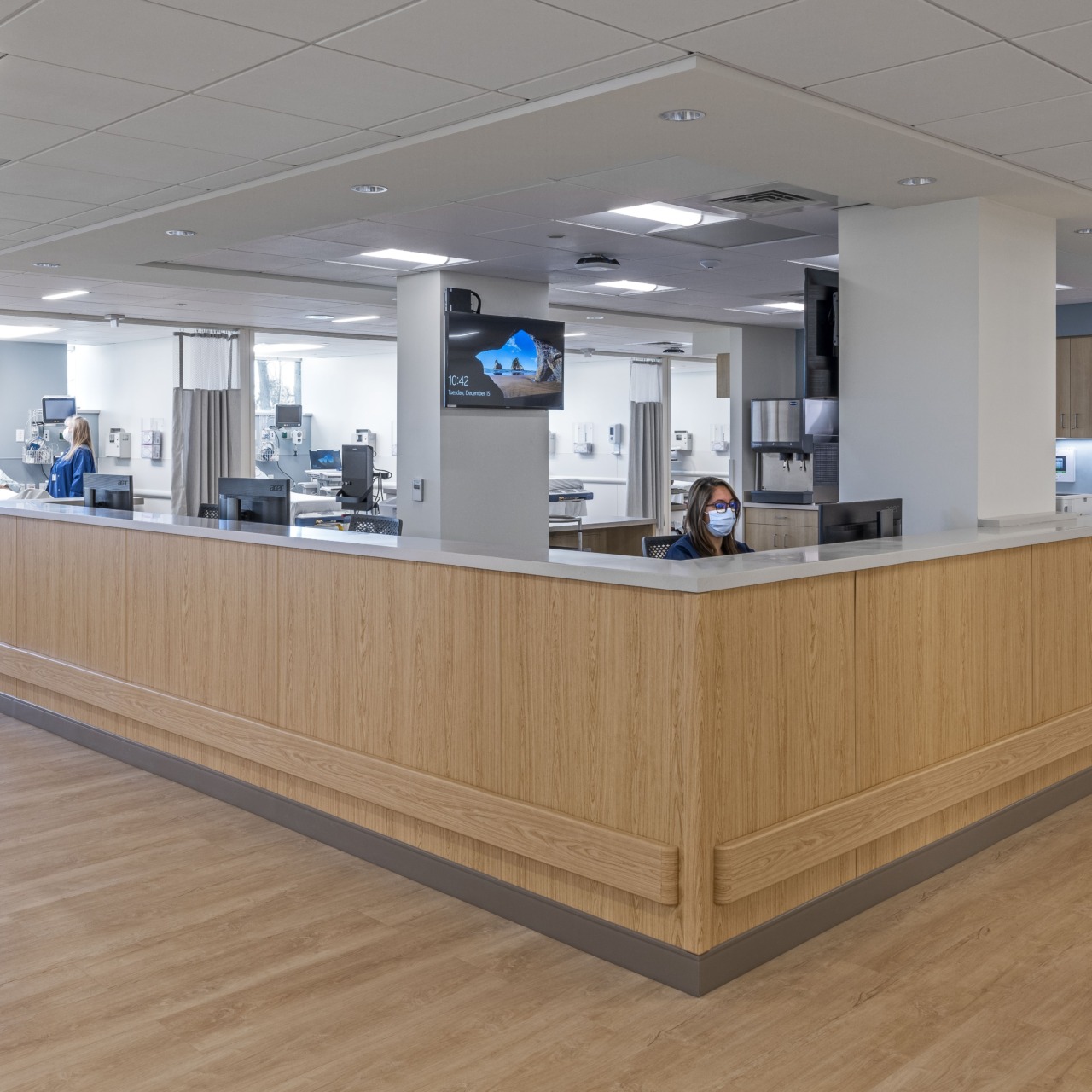 Hospital nurses' station with staff in scrubs and medical equipment in a clean and modern healthcare environment.