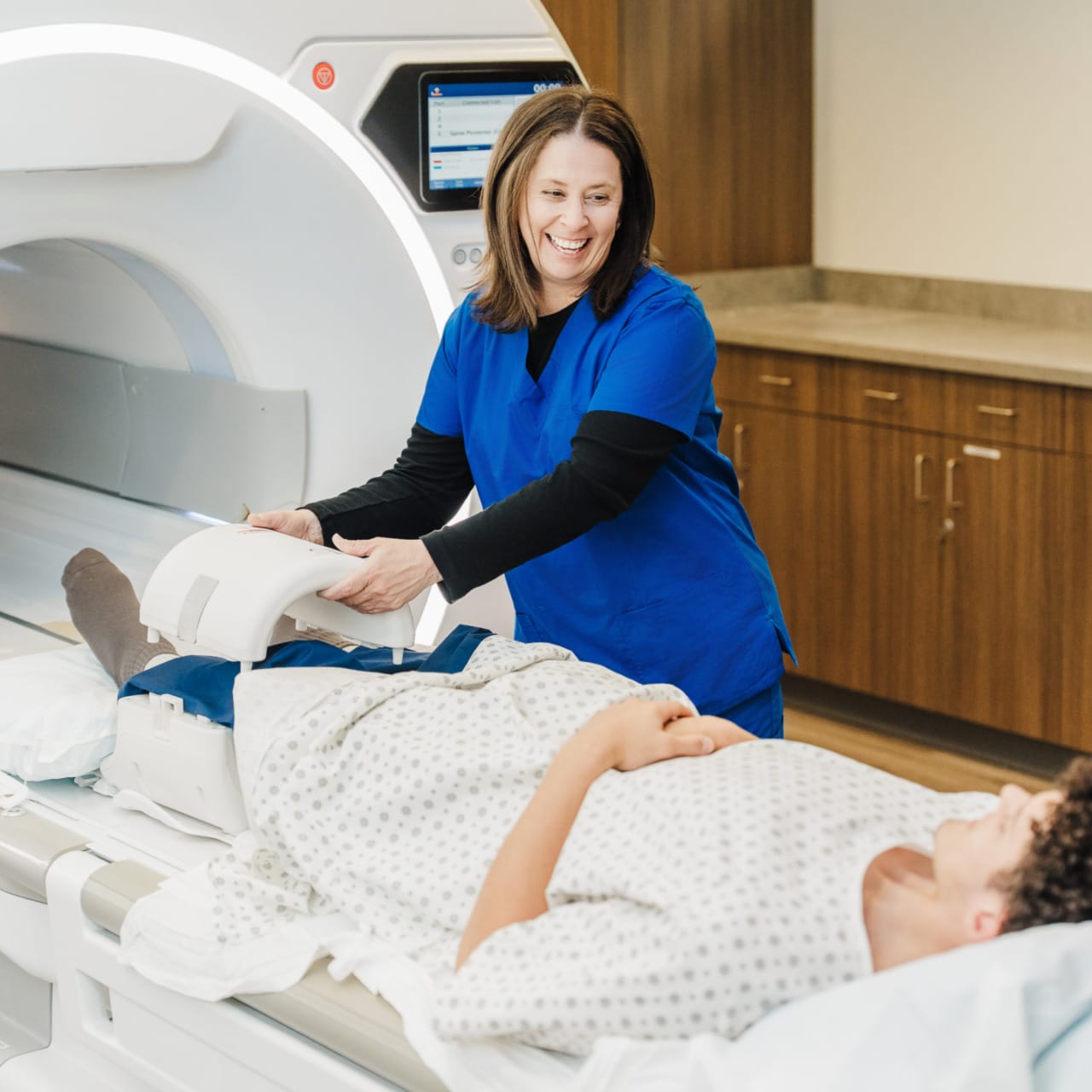 Medical professional prepares patient for MRI scan in modern hospital imaging room.