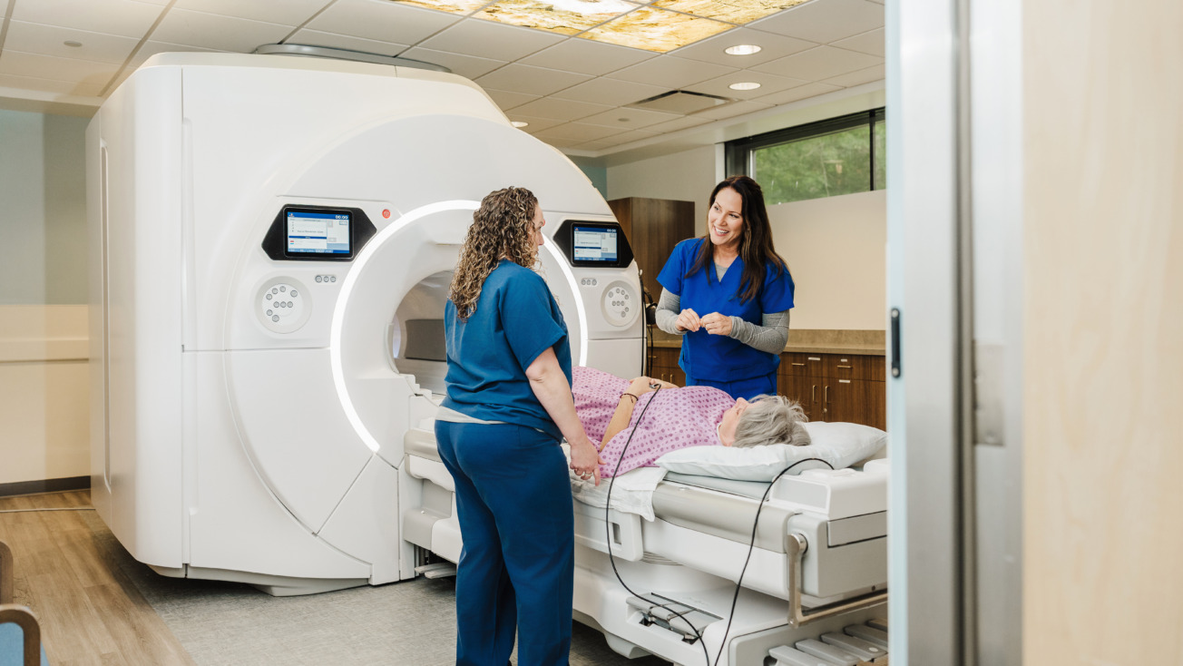 Medical staff assisting patient into MRI machine in modern hospital room.