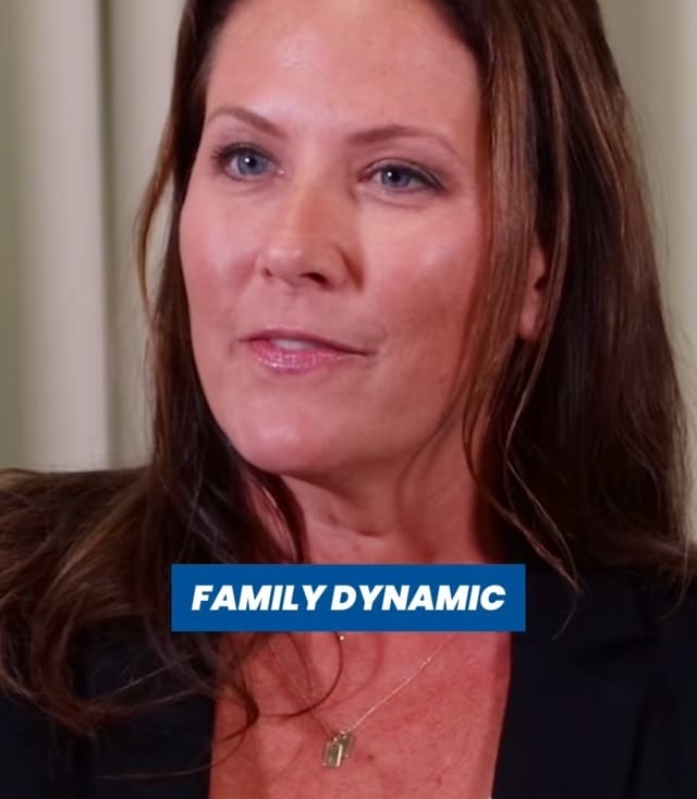 Person with long hair speaking on a topic related to family dynamics in an indoor setting.