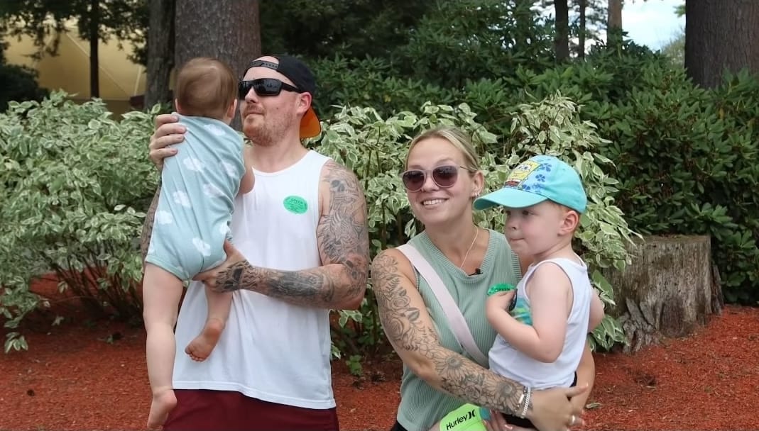 Family enjoying time outdoors with two small children, surrounded by greenery and trees.