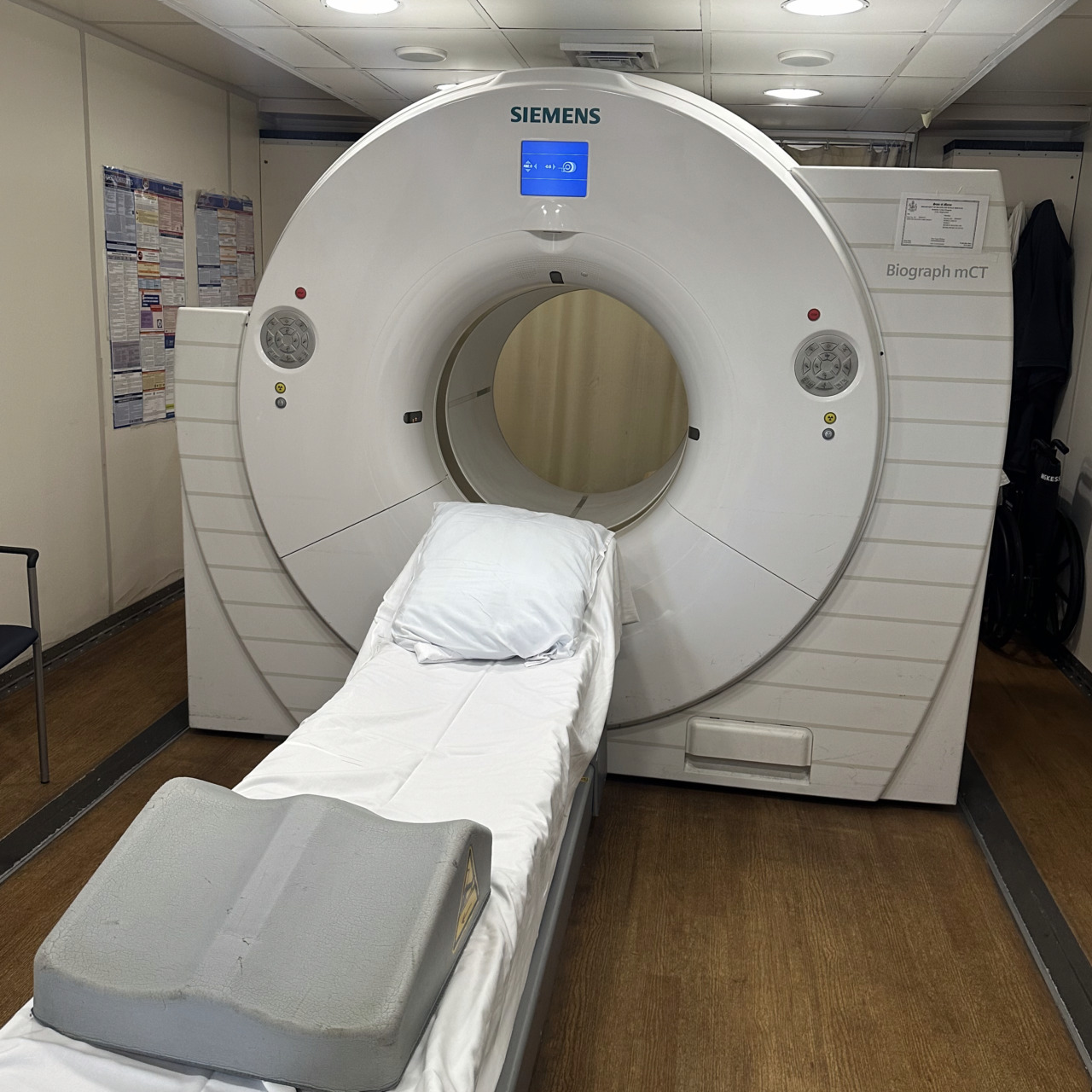 MRI machine in a hospital room with a patient bed in front.