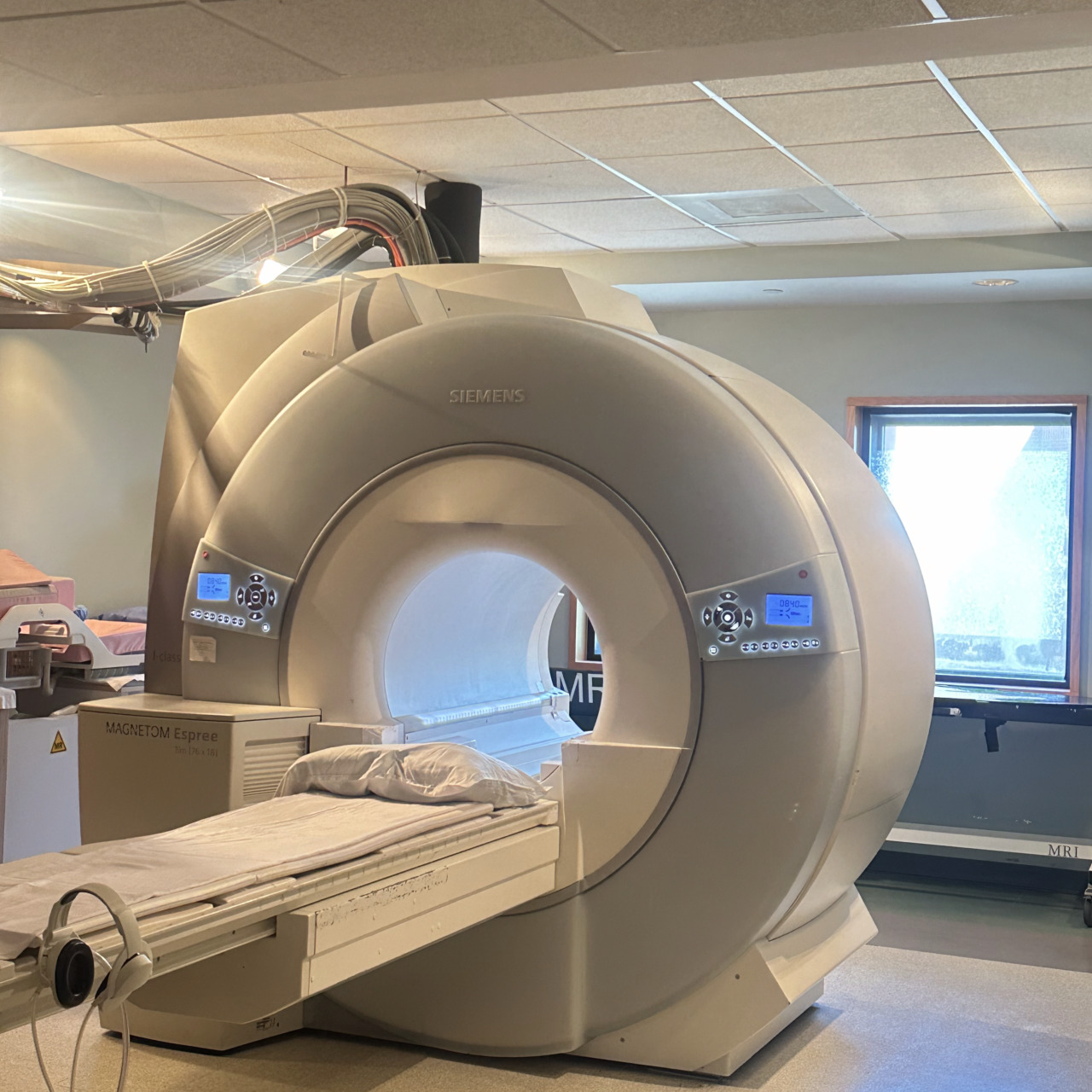 MRI machine in a medical facility with a patient bed in an empty, well-lit room.