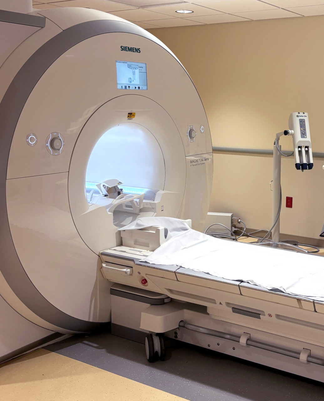 MRI machine in a medical facility room, ready for patient scanning and diagnostic imaging with a clean, prepared bed.