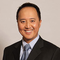 Smiling man in a suit with a light gray background