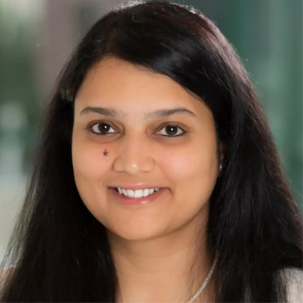 Person smiling with long dark hair in a professional indoor setting.