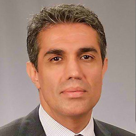 Man in a suit with short gray hair and a neutral expression against a plain background