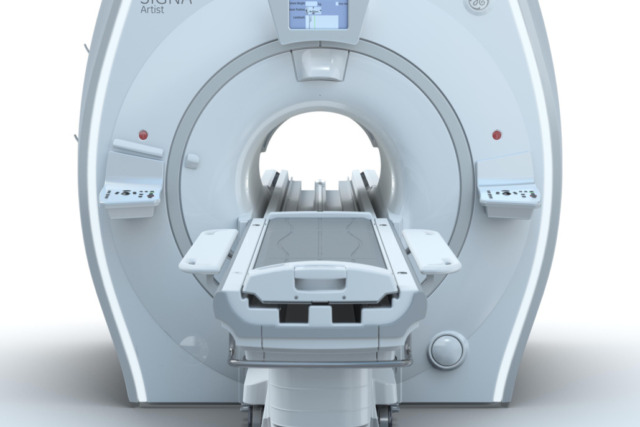 MRI machine in a hospital setting with a patient bed in front, ready for medical imaging procedures.