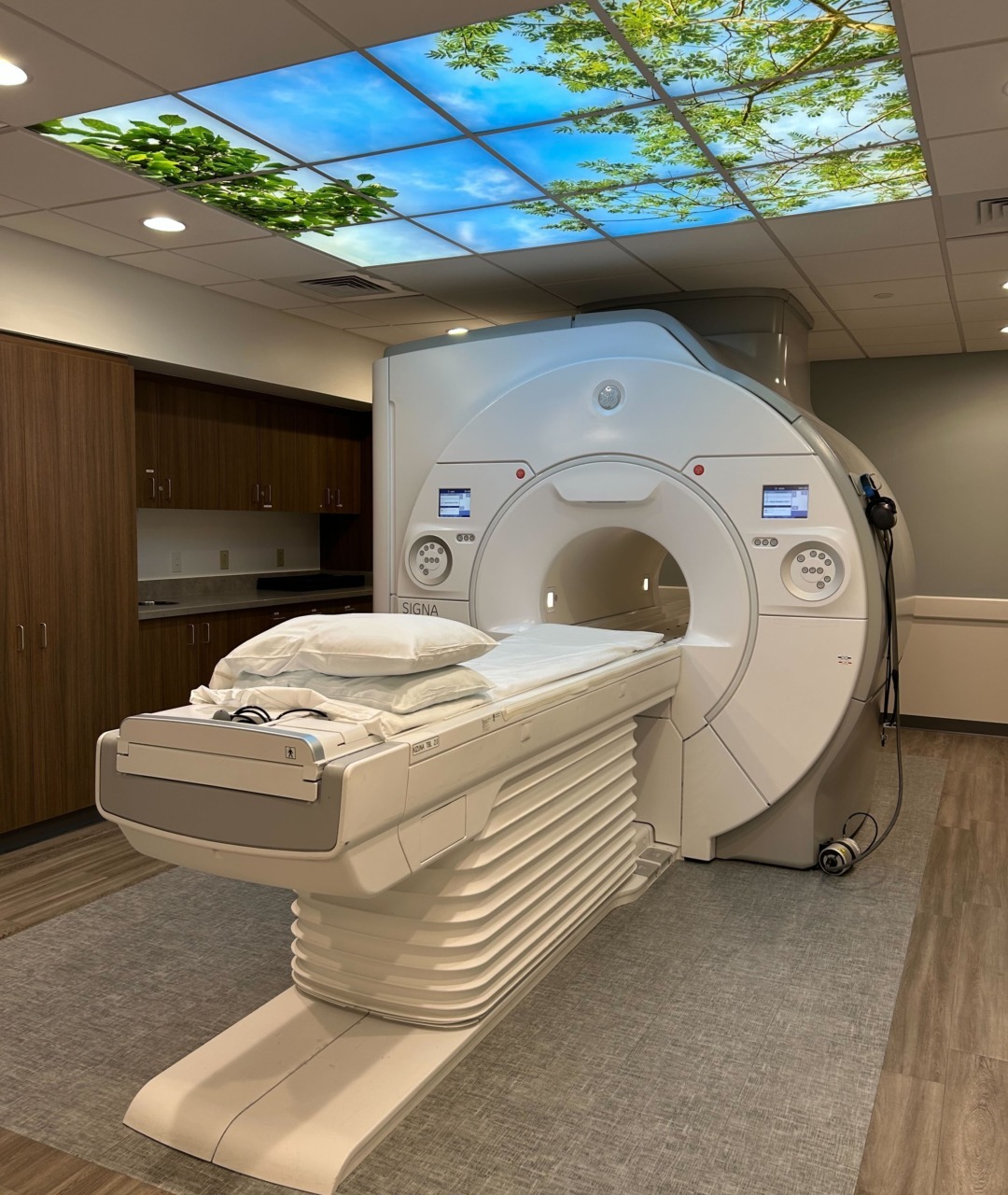 MRI machine in a medical facility with a scenic ceiling panel design to provide a calming atmosphere for patients.