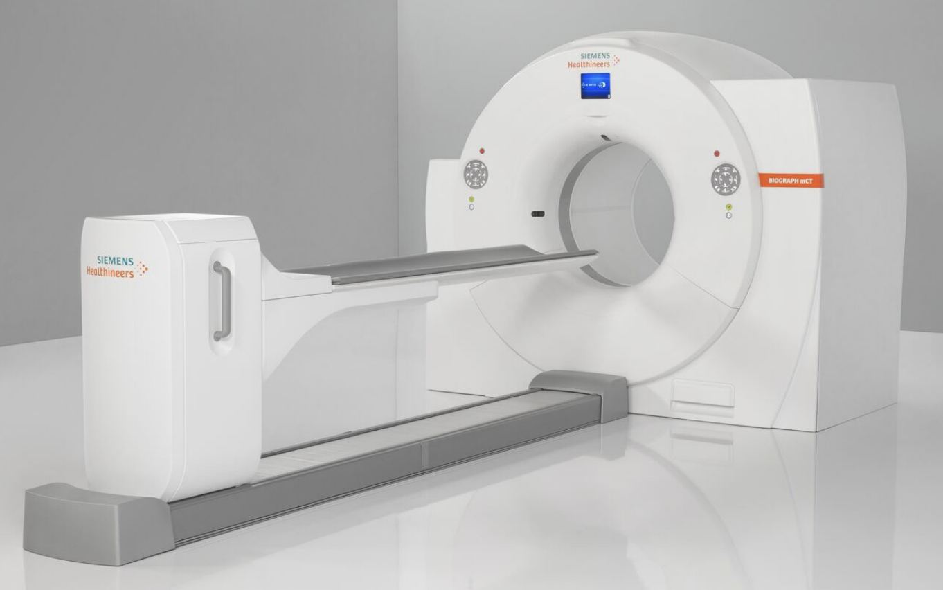 Modern CT scanner in a hospital setting with a sleek design, featuring a large circular opening and a patient table.