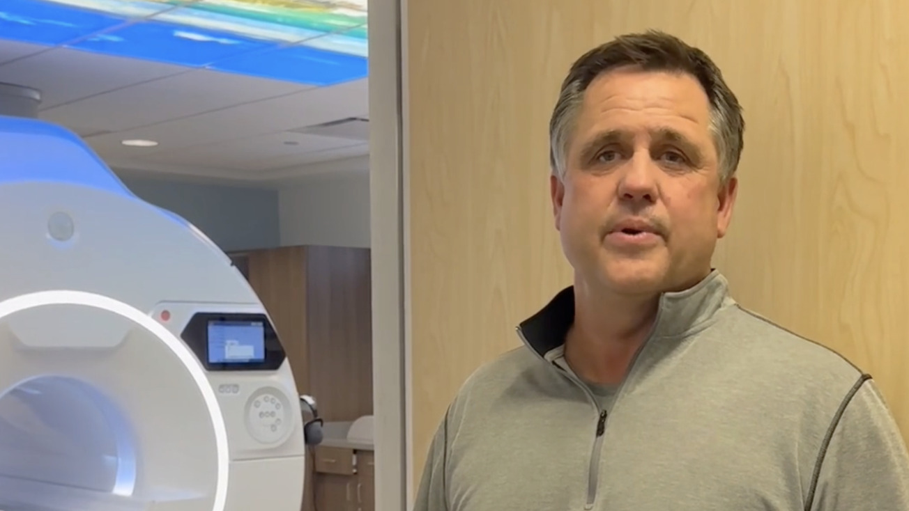 Person standing near an MRI machine in a medical facility room.