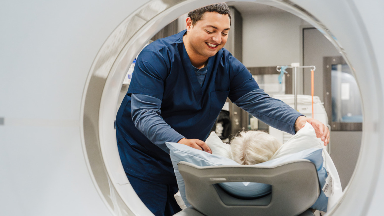Medical professional assists patient into MRI scanner, taken from inside the machine, showing a caring interaction.