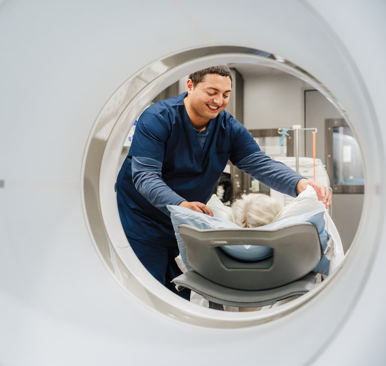 Medical professional assists patient into MRI scanner, taken from inside the machine, showing a caring interaction.