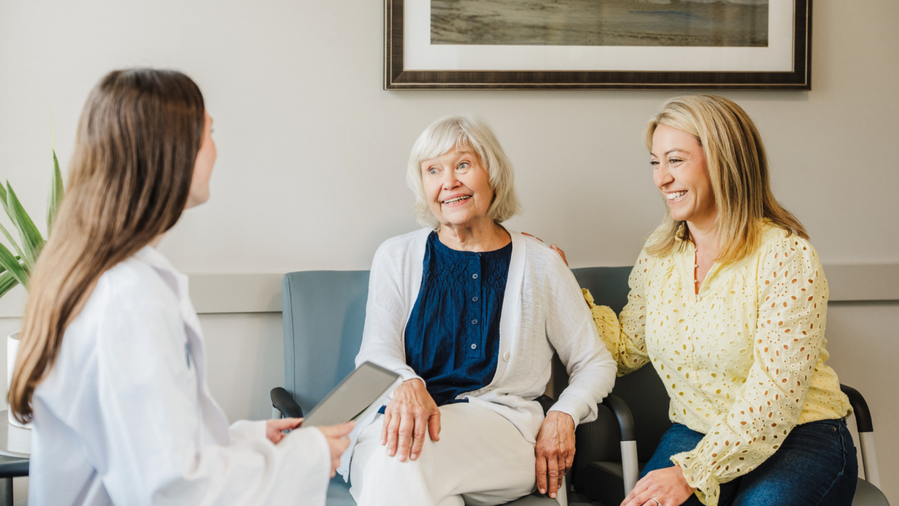 Doctor consulting with an elderly patient and her daughter in a clinic office setting