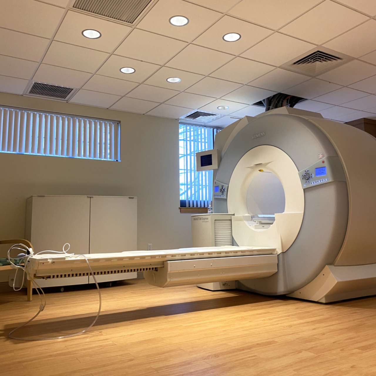 MRI machine in a hospital room with wooden floor and ceiling lights.