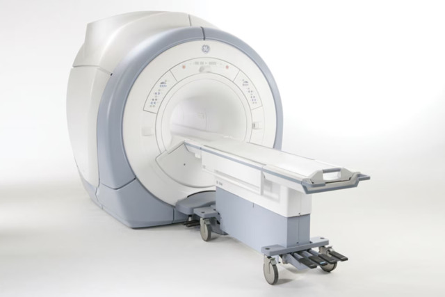 MRI machine with a sliding patient table in a hospital room.