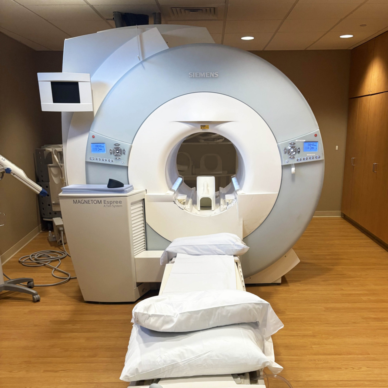 Modern MRI machine in a medical facility with wooden floors and neutral walls, ready for patient imaging.