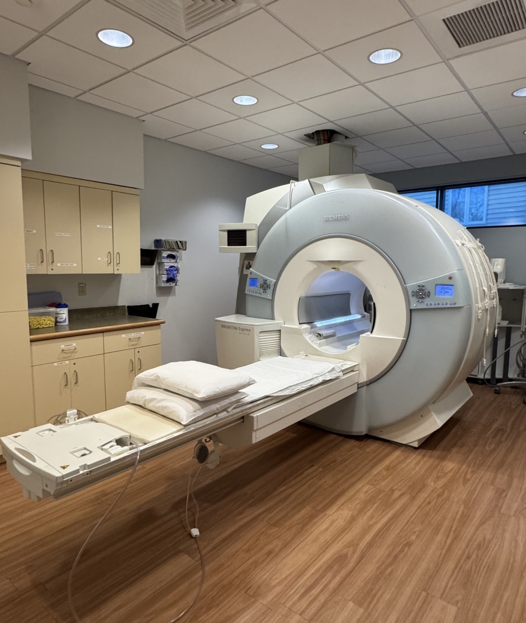 MRI machine in a hospital room with wooden flooring and cabinets