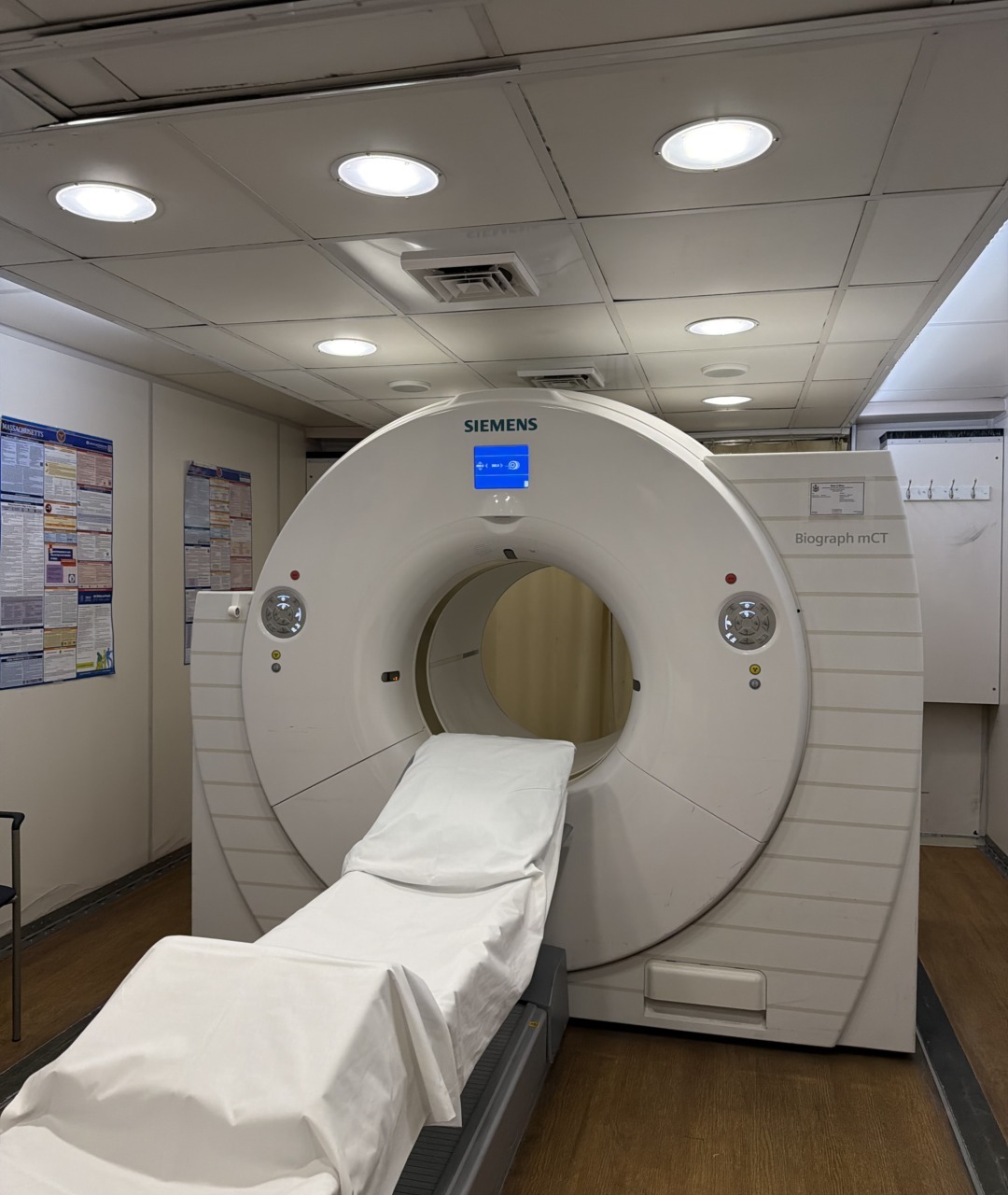 Hospital CT scanner machine with white cover in a medical examination room.