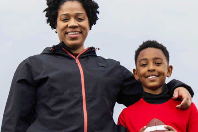 Woman and child smiling, child holding a football.