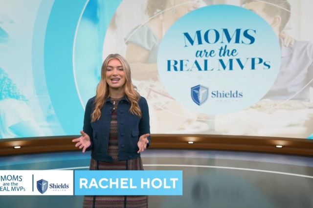 Woman presenting in front of a screen displaying the words "Moms are the Real MVPs" with Shields Health logo.