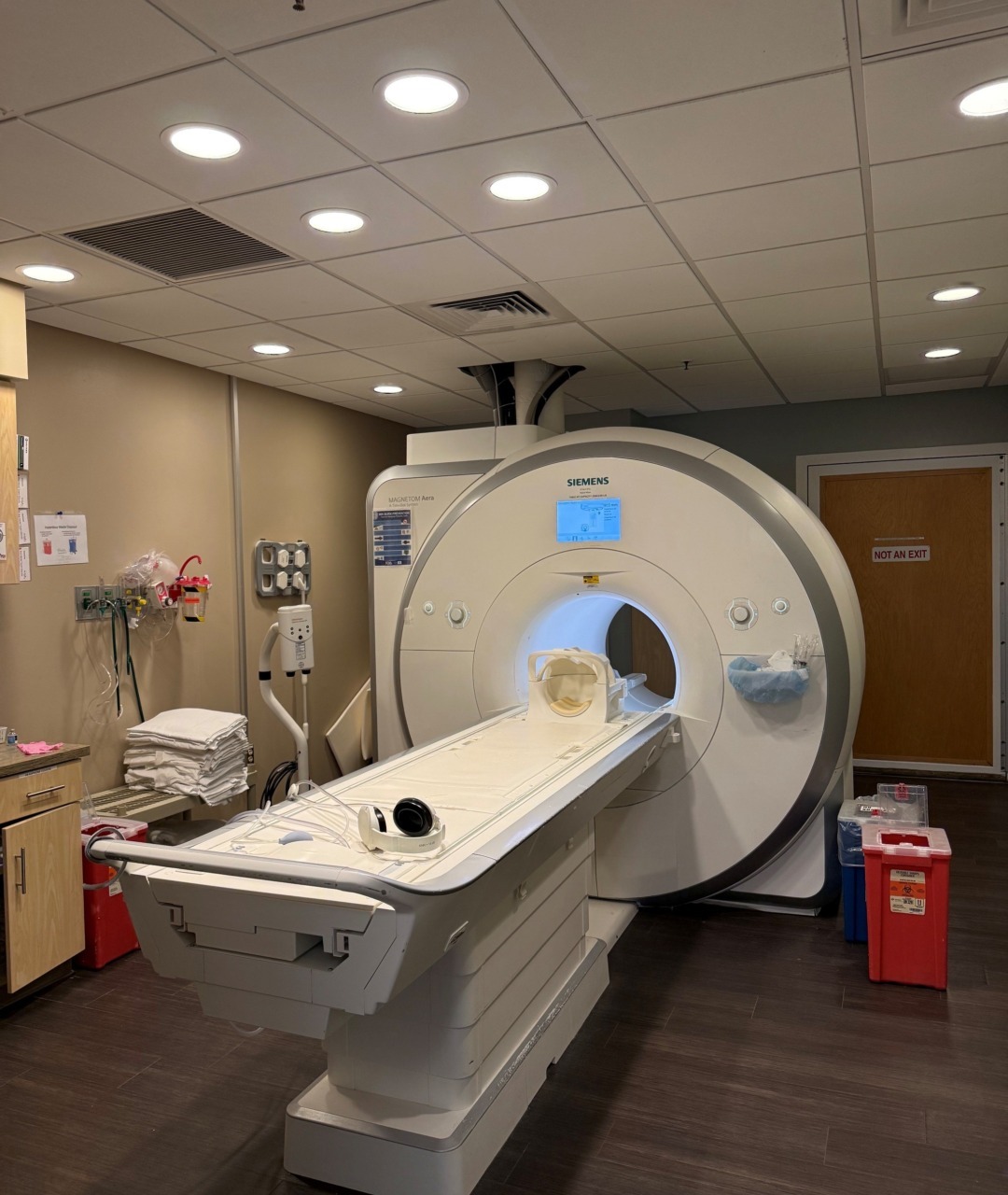 MRI machine in a medical imaging room with towels and medical equipment in the background.