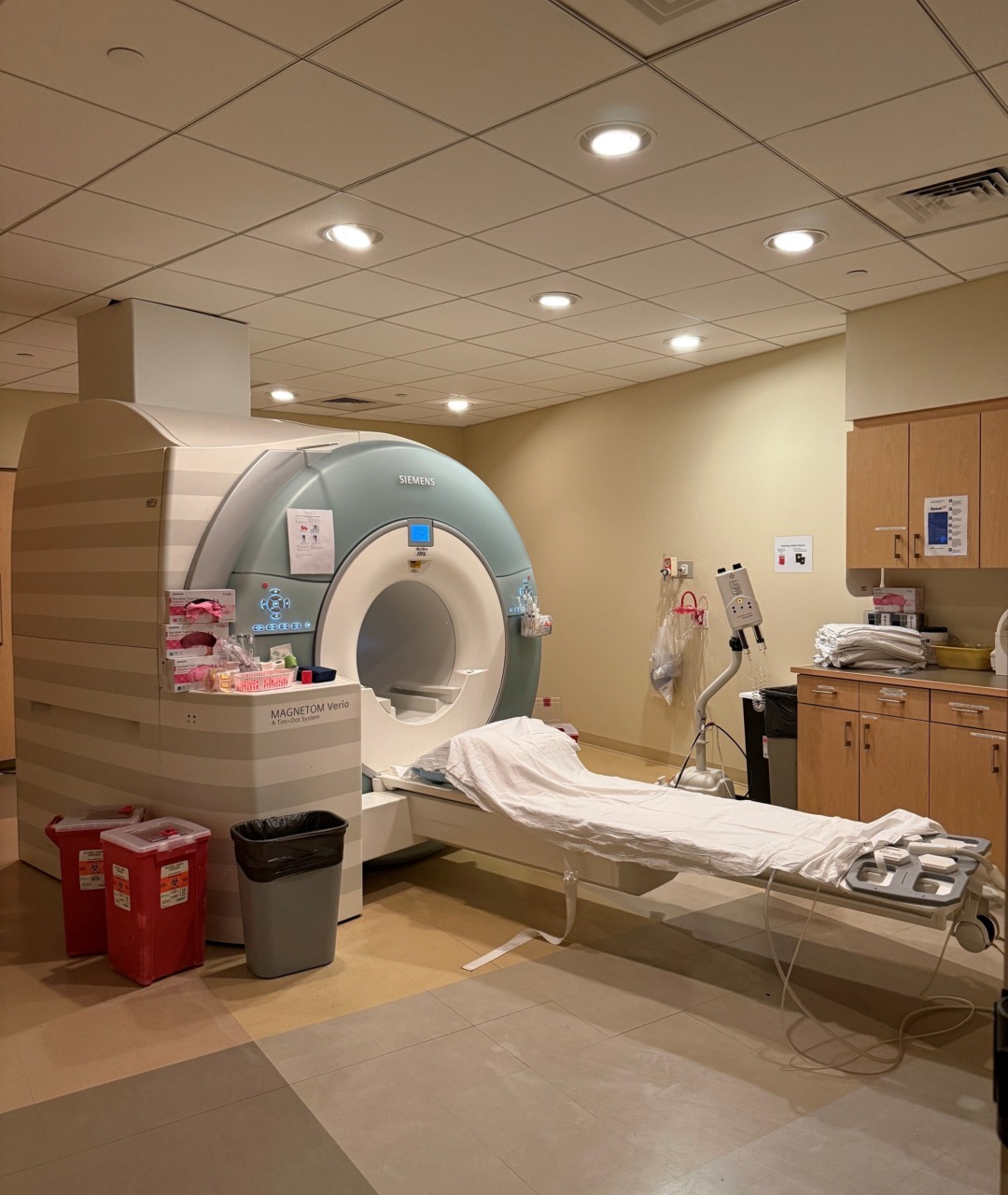 MRI machine in a hospital room with medical supplies and cabinets visible around it.