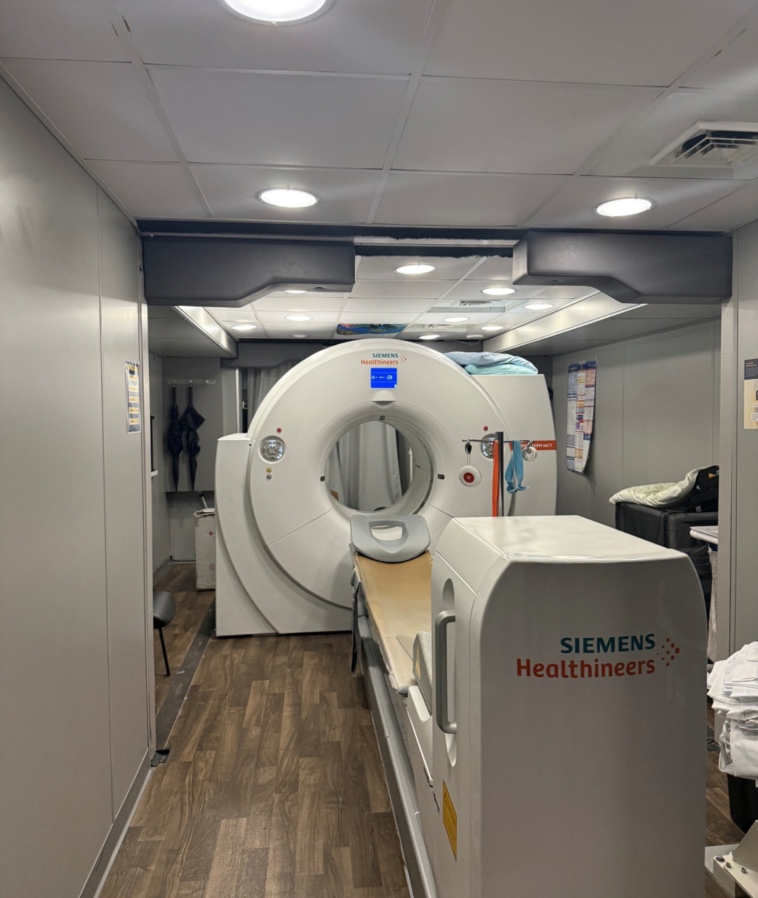 MRI machine in a medical facility with a wooden floor and soft overhead lighting.