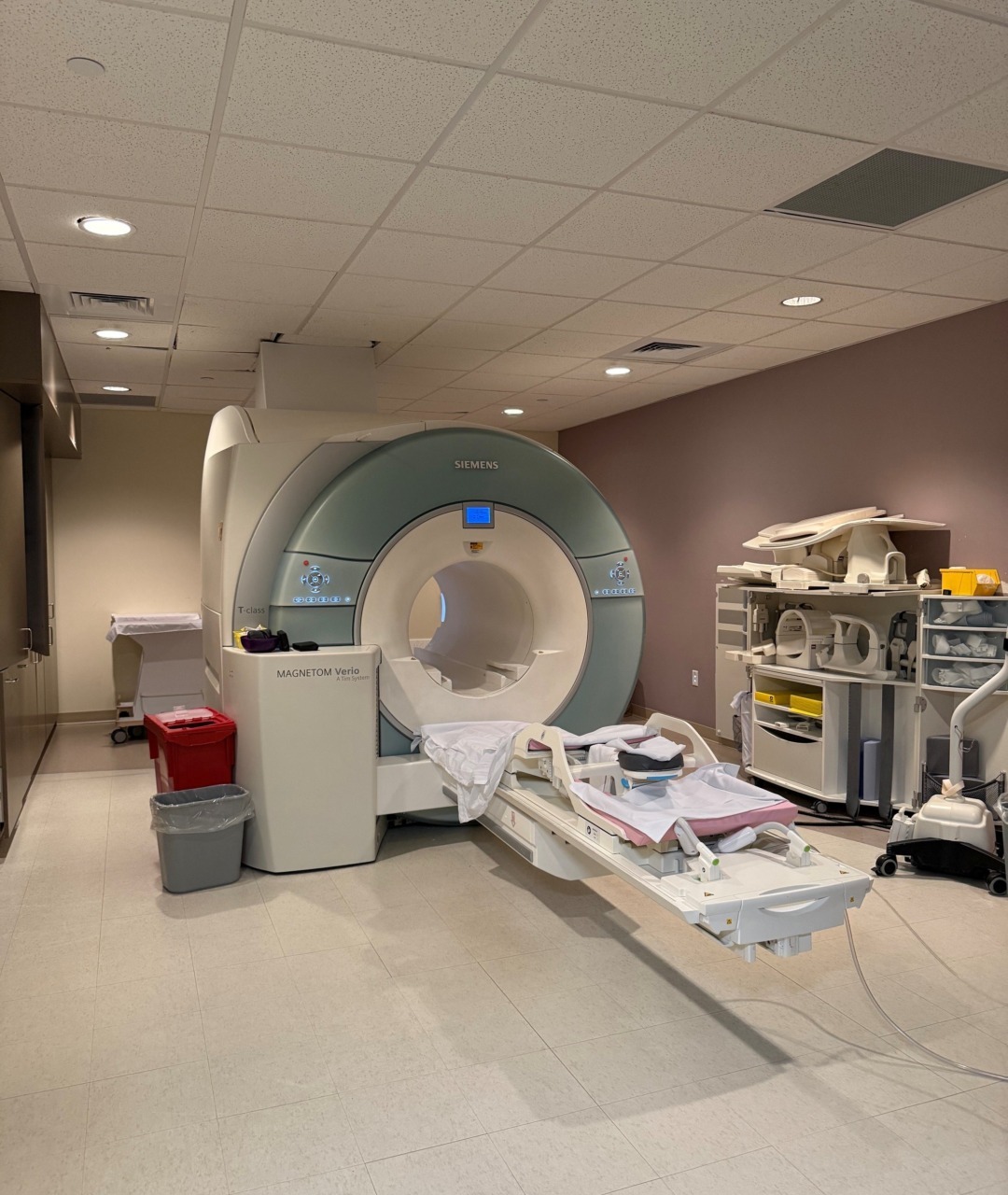 MRI machine in a medical room with equipment and supplies nearby.