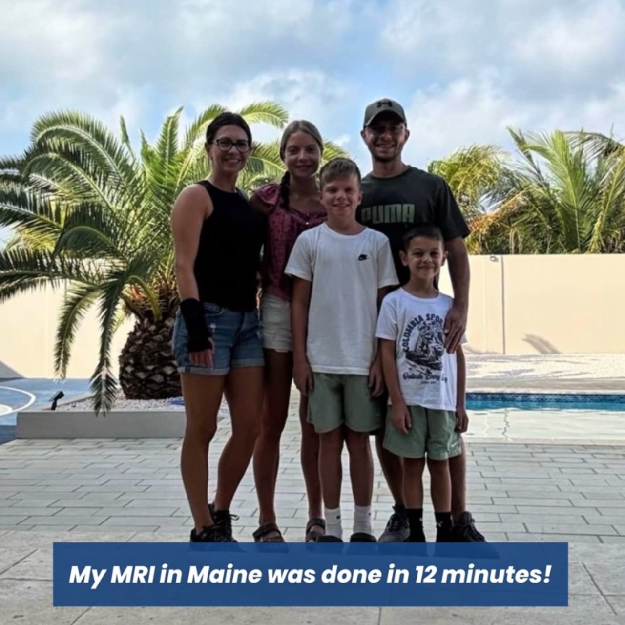 Family of five smiling by a poolside with palm trees in the background.
